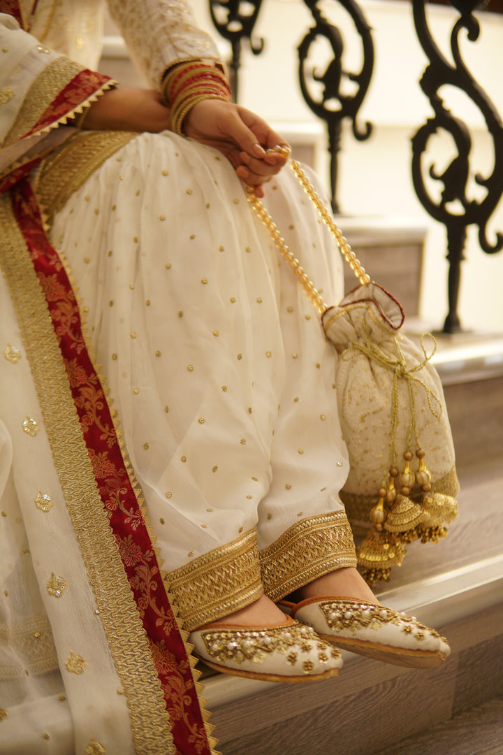 Designer 8-piece bridal set with gharara, potli bag, khussa footwear, and statement jewelry for mehndi or festive functions.