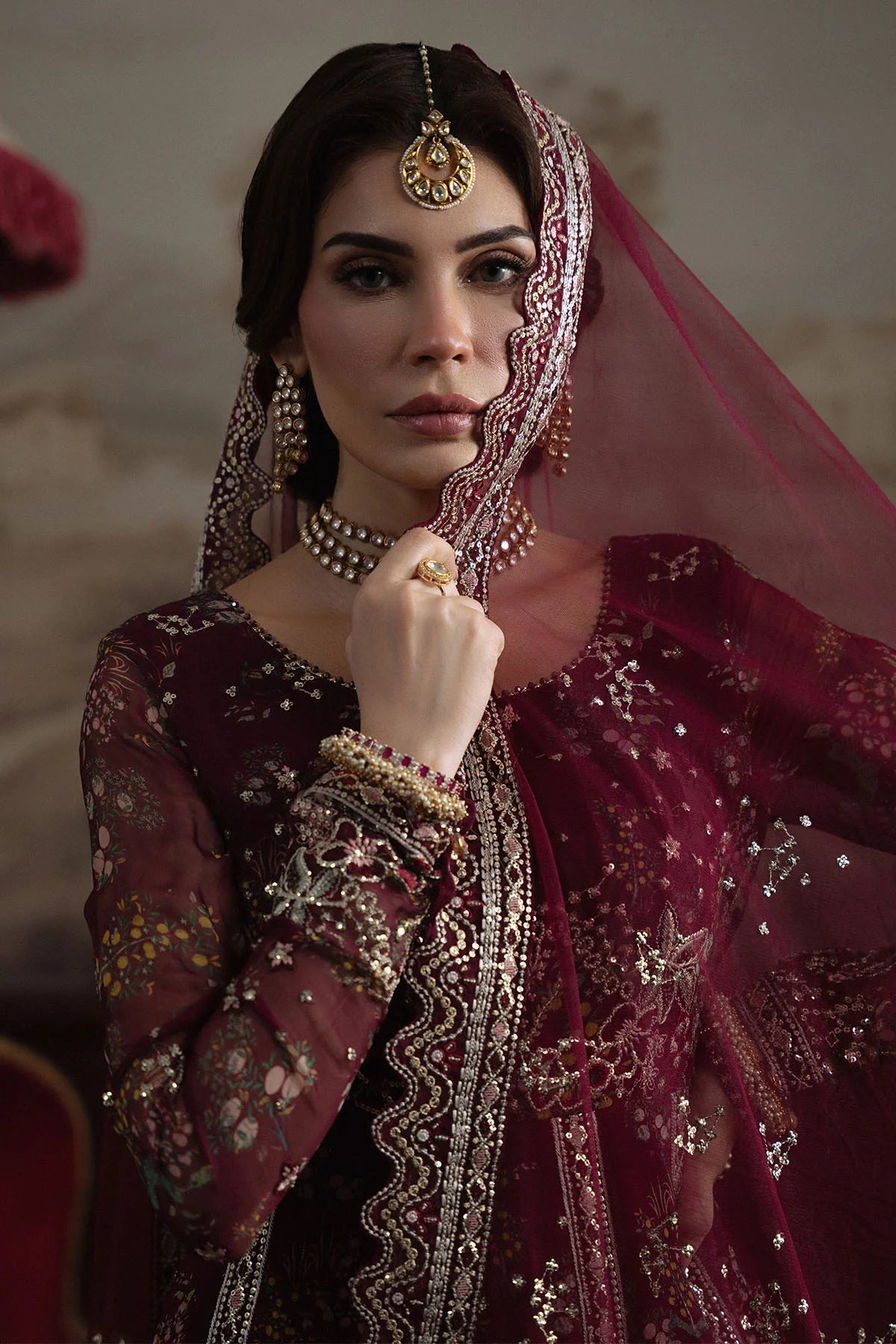 Side pose of model draped in maroon chiffon dupatta with zari and sequin work
