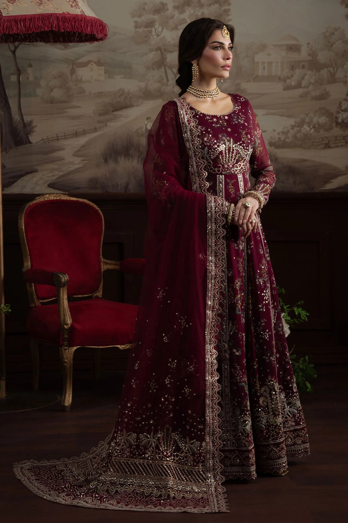 Model holding dupatta in traditional bridal pose wearing stitched maroon gown NEL-72
