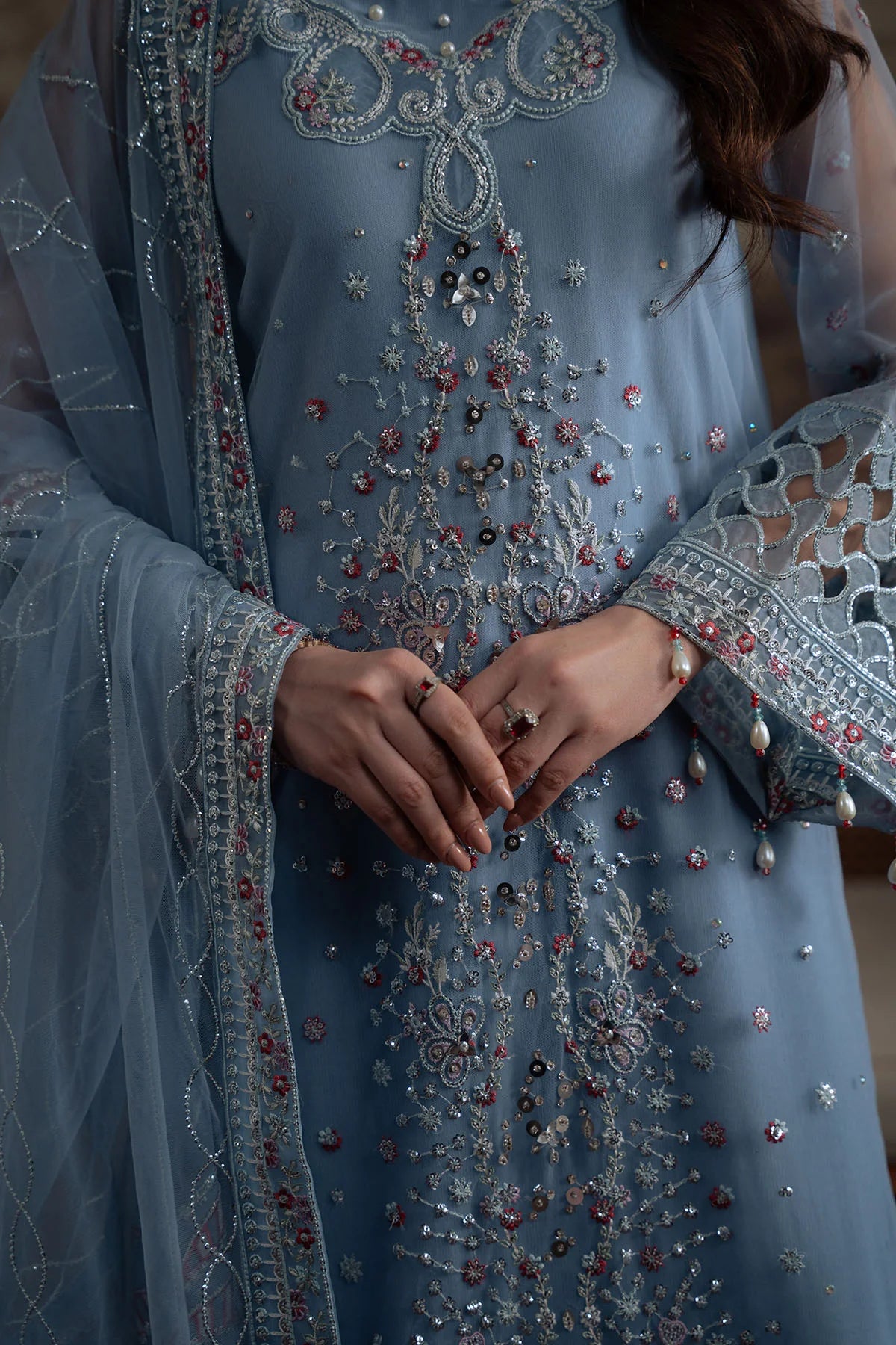 Detailed close-up of hand embroidery and pearl accents on the front panel of the Nureh suit