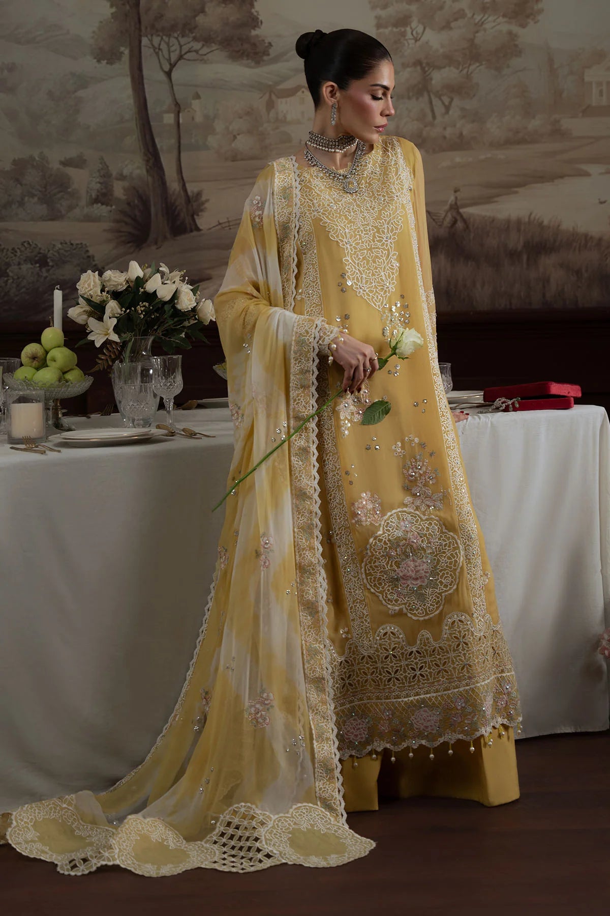 Side view of model in Nureh Style 76, holding white rose, showcasing dupatta drape and embroidery.
