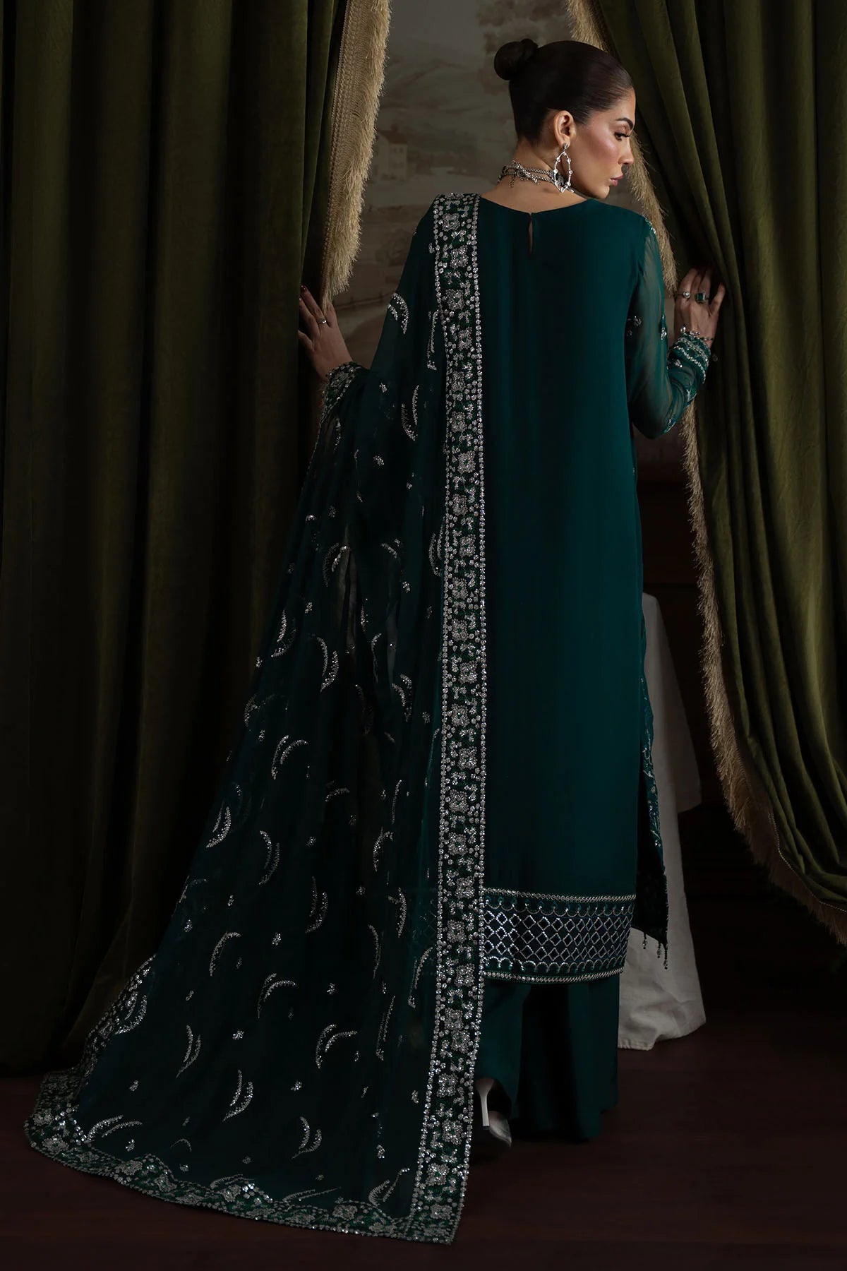 Back view of model wearing deep green chiffon suit with plain dyed back and fully embroidered dupatta border